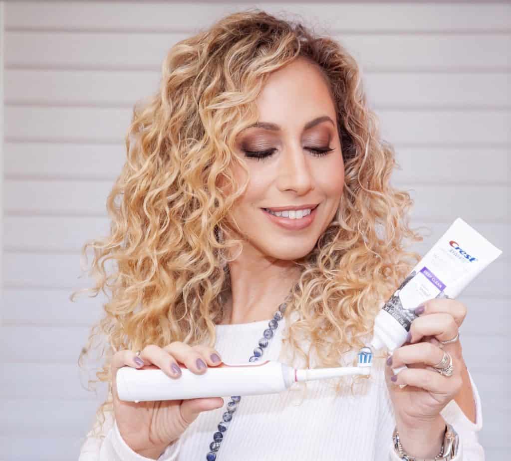 woman holding toothbrush and toothpaste to make teeth whiter