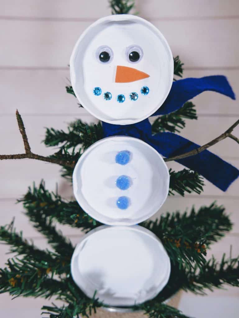 This upcycled snowman made from jar lids is an excellent craft that anyone can do. Kids will love helping decorate your home with it!