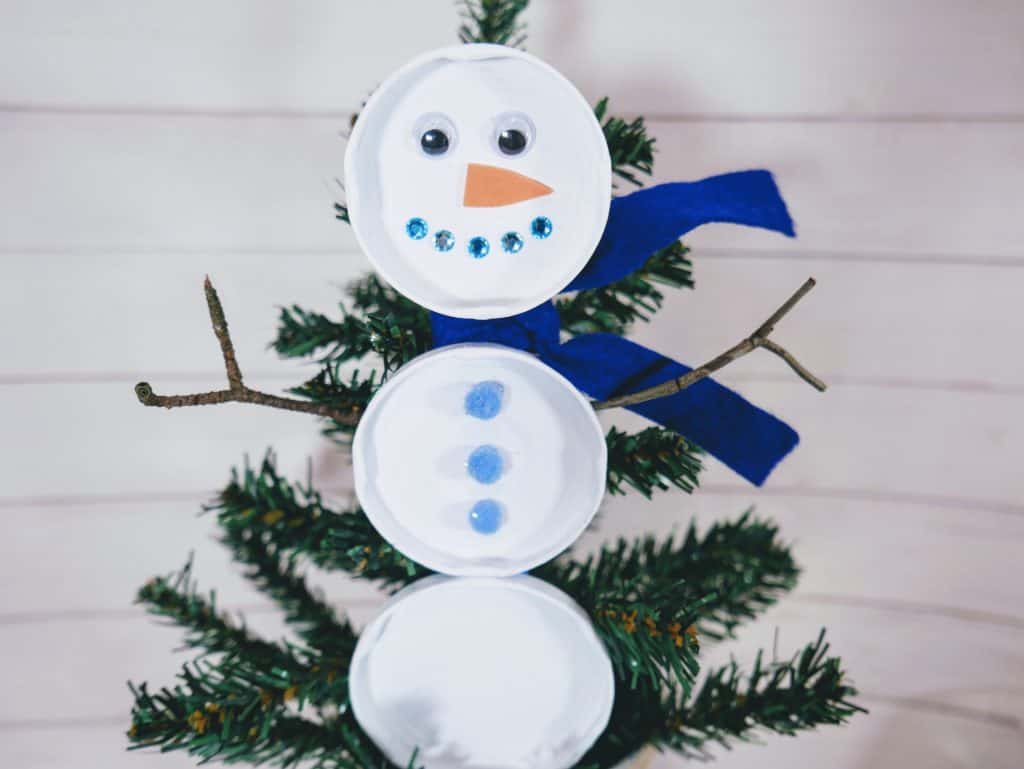 This upcycled snowman made from jar lids is an excellent craft that anyone can do. Kids will love helping decorate your home with it!