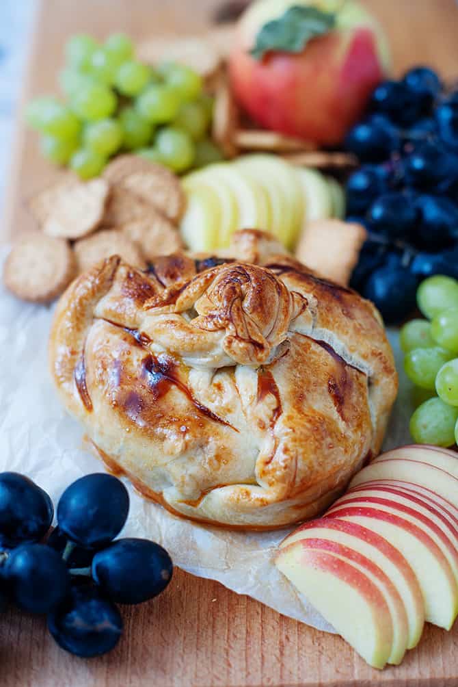 Baked Brie in puff pastry with a cutting board with sliced grapes and apples