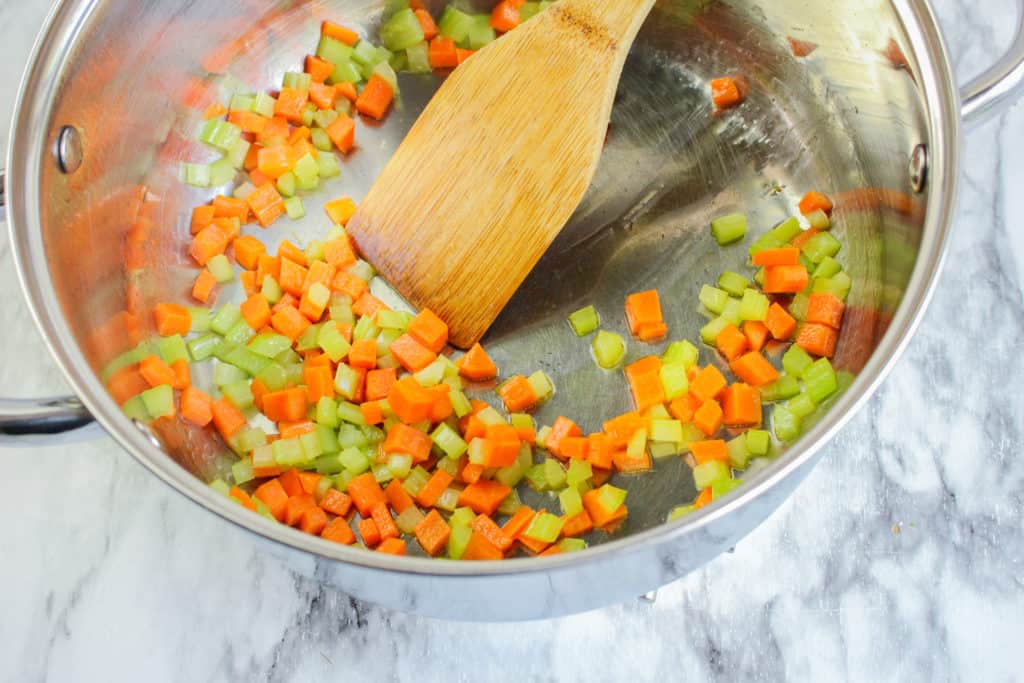 carrots and celery in a pan with a wooden spoon