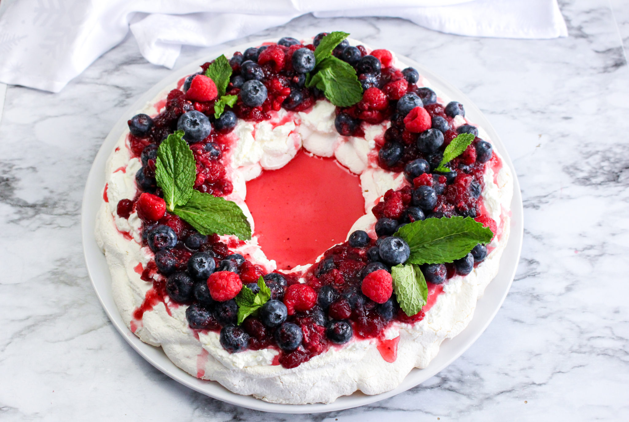 This delicious holiday meringue wreath is a great addition to any Christmas table. The raspberries and blueberries add so much color and flavor!