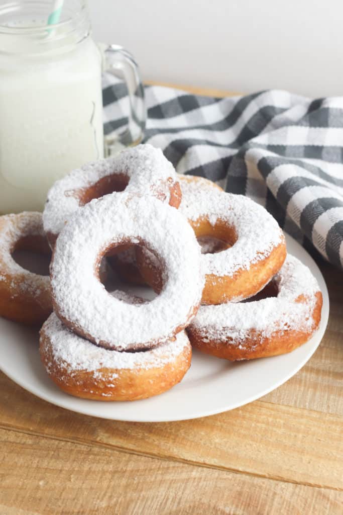 stack of powdered sugar biscuit donuts on a white plate 