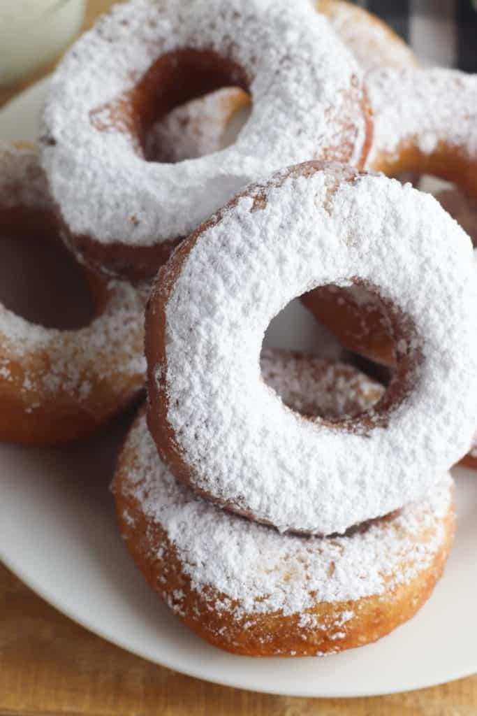 Close up image of a stack of powdered sugar biscuit donuts 