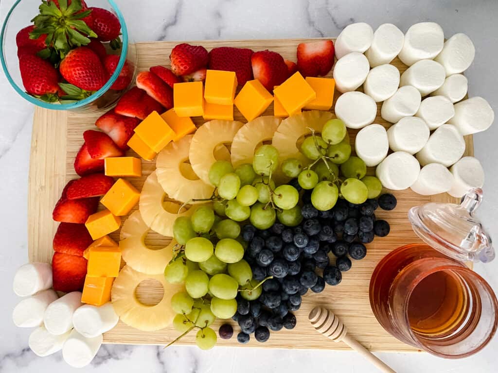 Rainbow fruit board with marshmallows and honey