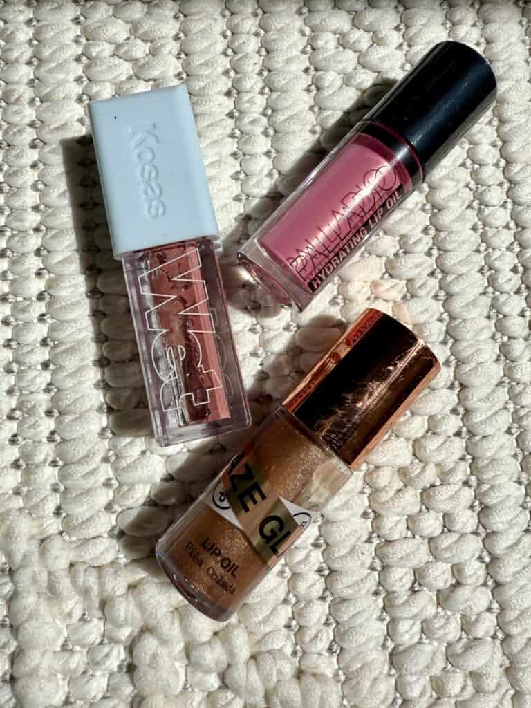 Three lip oils on a white blanket